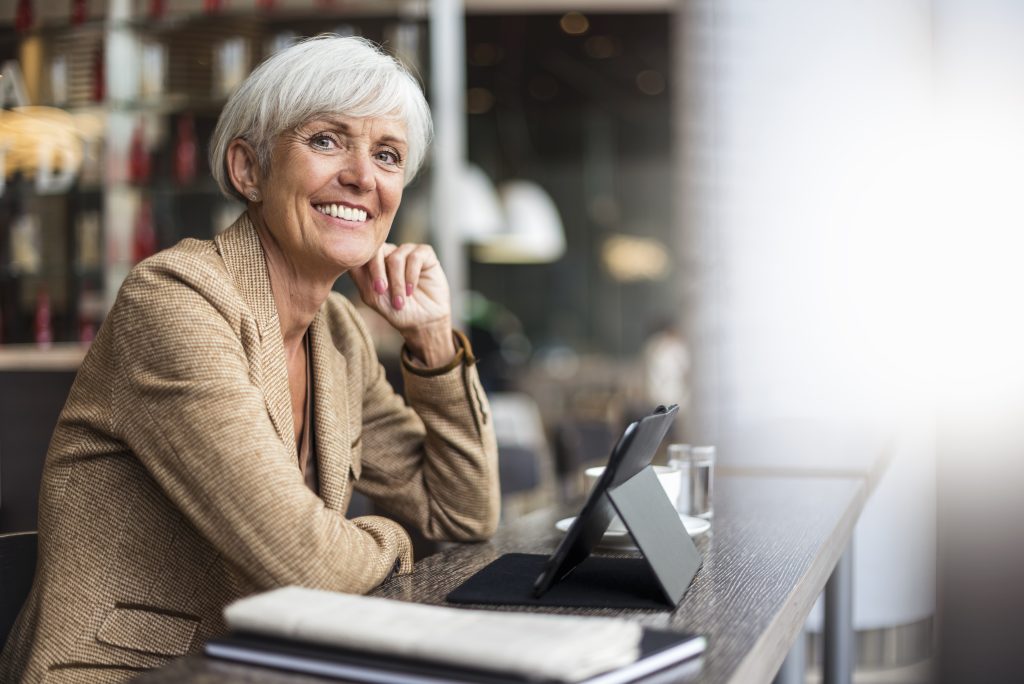 Portrait of smiling business person with tablet in a cafe